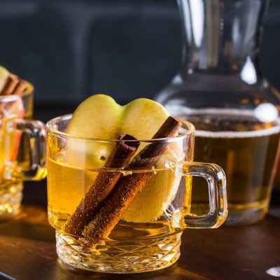 Front view of Hot Apple Cider Cocktail garnished with Cinnamon sticks and an apple slice