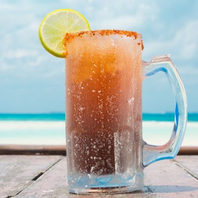 Beer glass of Mexican Michelada cocktail at the beach