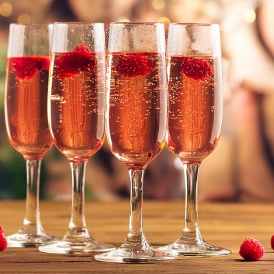 Three Kir Royale French cocktails served in flute glasses with raspberry garnish