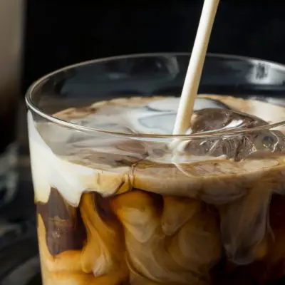 Close up of double cream being poured into a White Russian cocktail