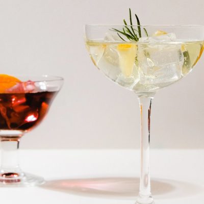 Close up front view of cocktails in different glasses against a white backdrop