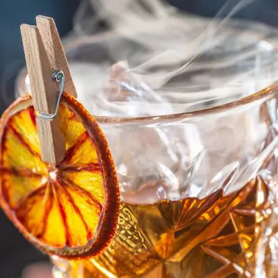 Old Fashioned smoking with dried orange garnish