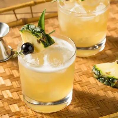 Refreshing boozy Mai Tai cocktail on the rocks with cherry and pineapple garnish