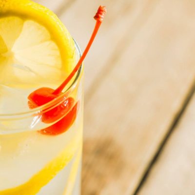 close up of a vodka collins from above with orange and cherry garnish