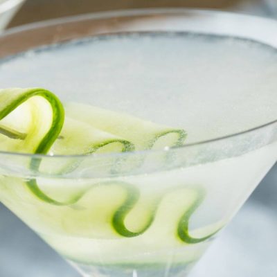 Cucumber martini close up with a sliver or cucumber on a cocktail pick