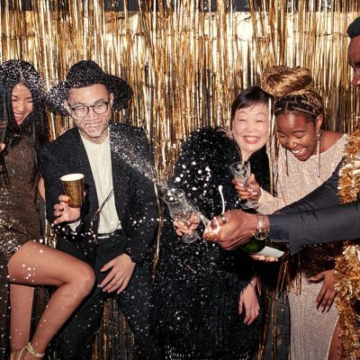 Friends opening a bottle of Champagne at New Year's Eve party