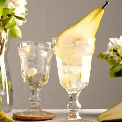 Pear Martinis with sliced pear garnish against a neutral backdrop with fresh pears in the foreground