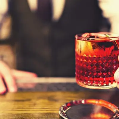 Bartender serving a bright red Negroni cocktail