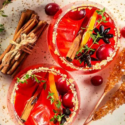 Sweet cranberry cocktails with sugared rim and cinnamon garnish