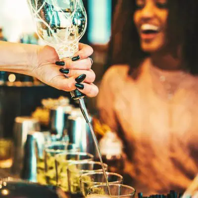 A bartender with black nail varnish speed-pouring vodka into glasses at London Cocktail Week