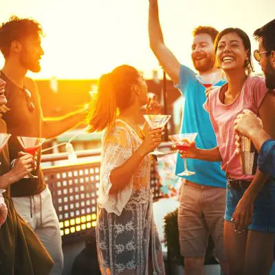 Friends enjoying popular cosmopolitan cocktails at a rooftop party