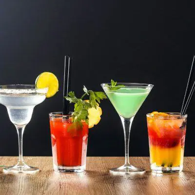 A line up of colourful cocktails in different glasses