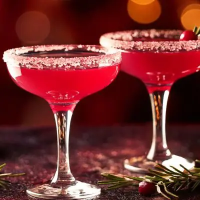 Two vibrant pink Mistletoe Martinis with cranberry and rosemary garnish