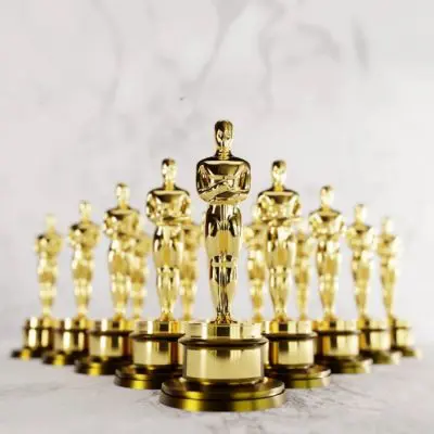 A series of Academy Awards Oscars statues standing in formation against a white marble backdrop