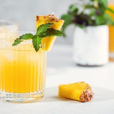 Two refreshing Pineapple Vodka cocktails on ice with mint garnish