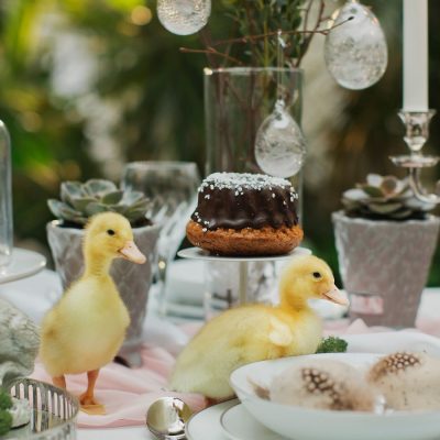 A beautiful Easter table set with crystal stemware and candles, and a few fluffy chicks having a whimsical moment in the midst of it all