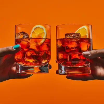 Two hands clinking together Negroni cocktails