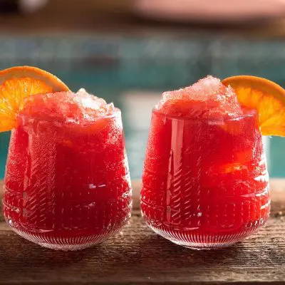 Two Frozen Negroni cocktails with orange garnish, served poolside