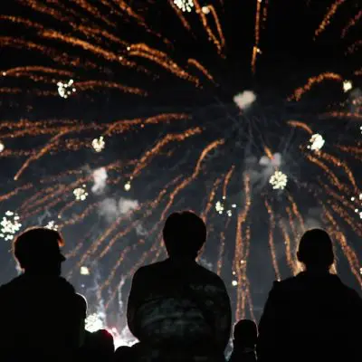 Wide shot of a group of friends in sihouette watching fireworks at a New Year's Eve party