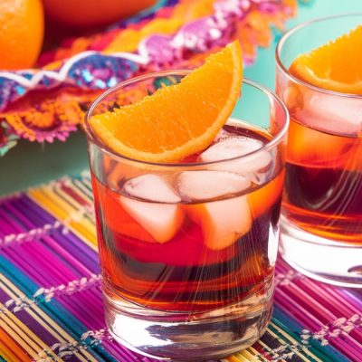 Two Oaxacan Negroni cocktails on a colourful placemat for Cinco de Mayo