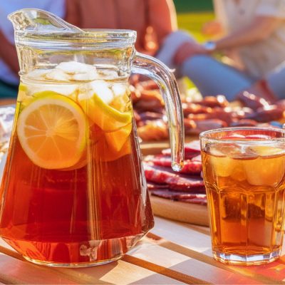A jug of Southern Sweet Tea summer mocktails served with picnic foods in a picnic setting