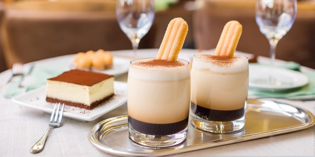 Close up of two Tiramisu White Russian variations served with lady finger biscuit garnish and a slice of tiramisu on the side