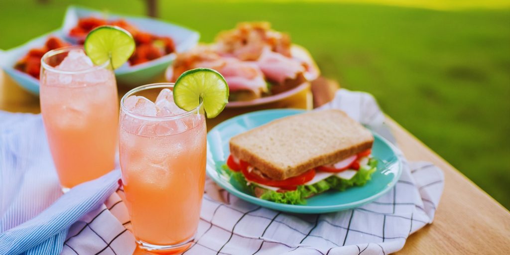 Two Strawberry Daiquiri Spritz mocktails served with a BLT sandwich at a garden party