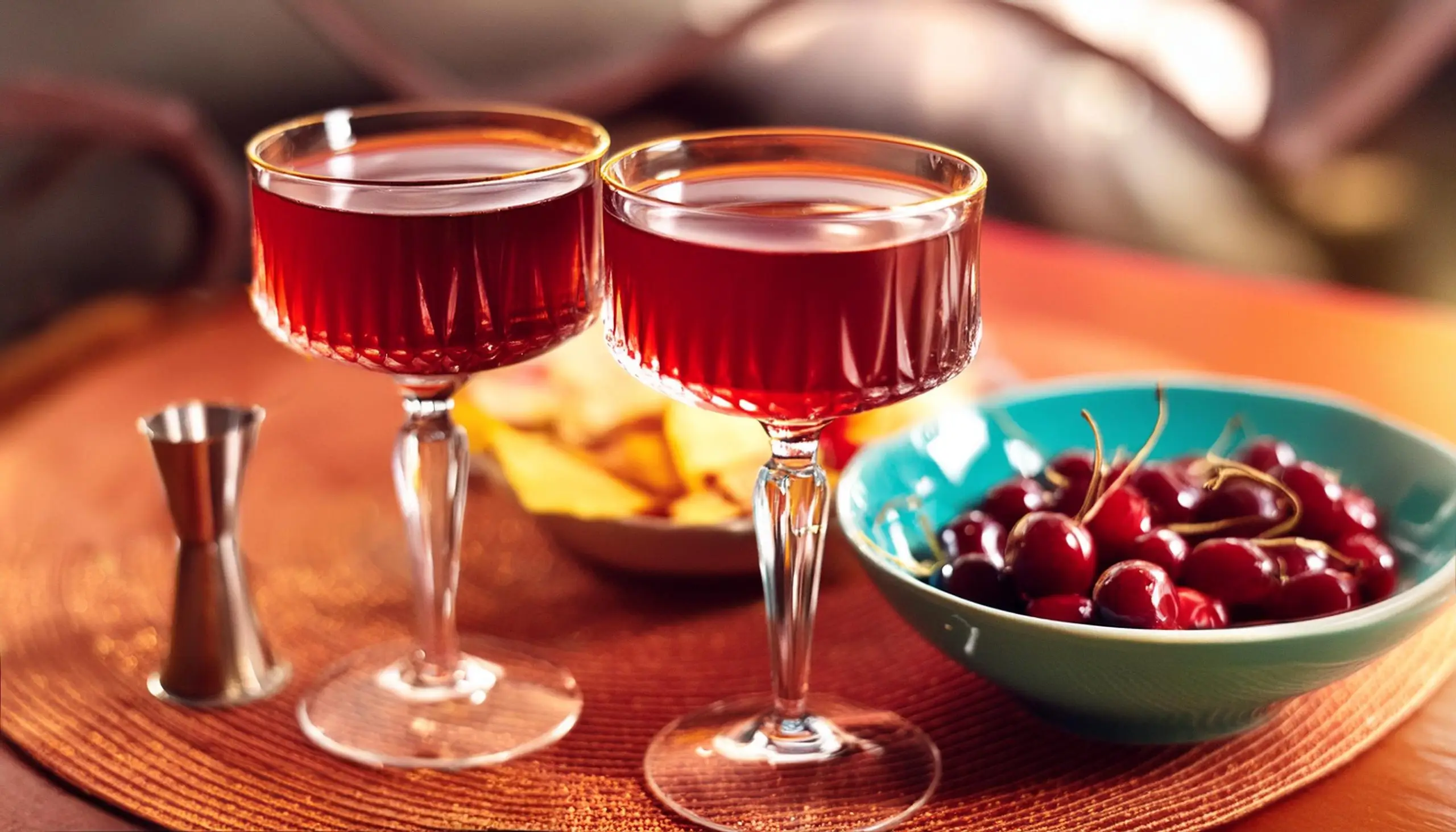 Close up of two Añejo Tequila Manhattan cocktails with a bowl of Luxardo cherries