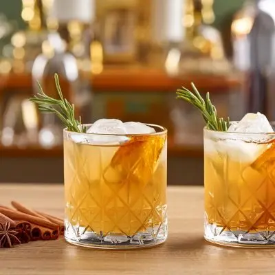 Two Anejo Tequila cocktails with rosemary and orange garnish