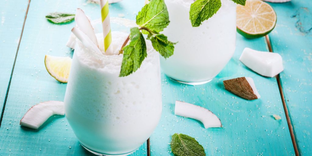 Two muddled Coconut Mojito cocktails with fresh mint garnish