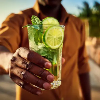 A man holding a Cuban Mojito cocktail to camera