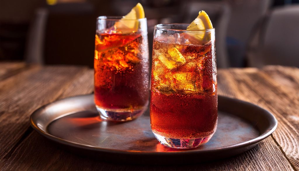 Two Americano cocktails with lemon garnish on a tray in a modern lounge setting