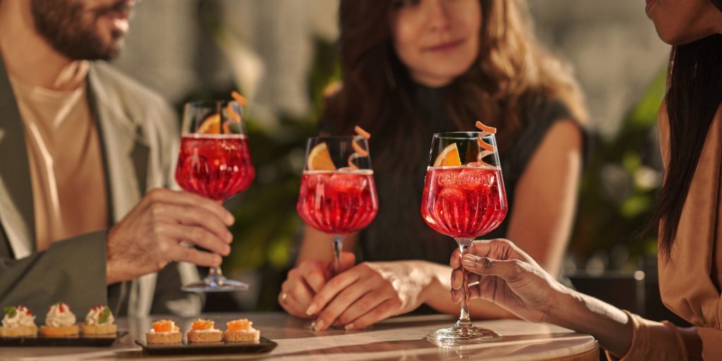 Three people enjoying Campari Spritz cocktails