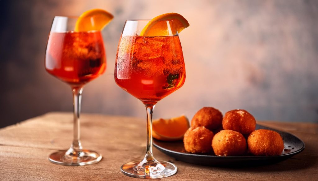 Two Campari Spritz cocktails served with arancini