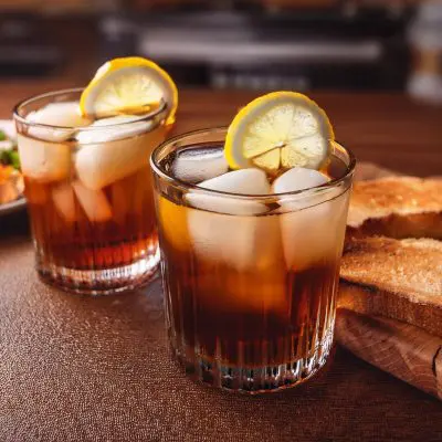 Two Cynar Negroni cocktails with lemon wheel garnish, served with bruschetta