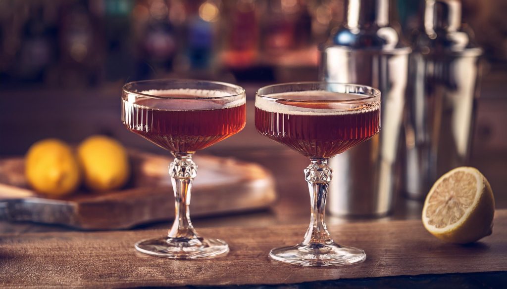 Two Intercontinental cocktails in coupe glasses on a wooden table in a modern home setting 