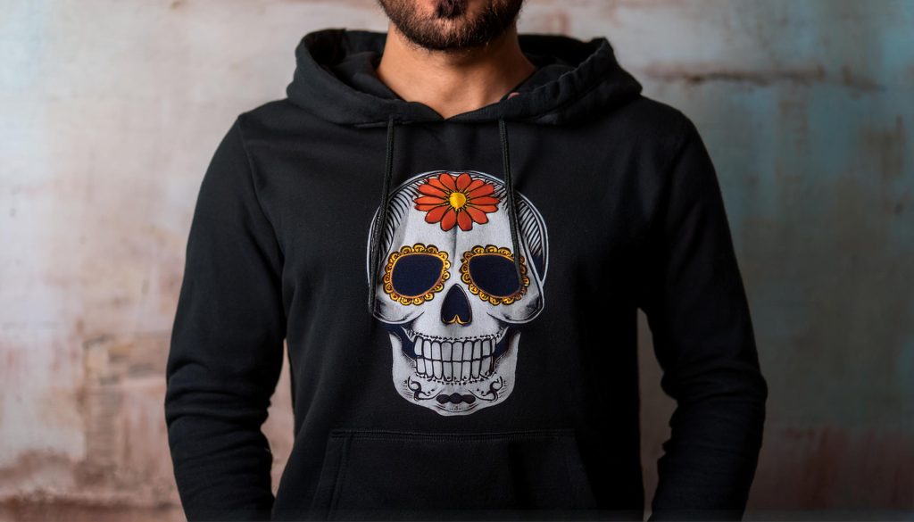 Close up of a man wearing a black hoodie with a sugar skull design on it