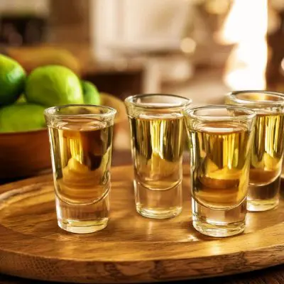 A tray of four reposado tequilas for sipping neat, blurred out modern kitchen in the background