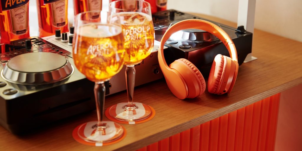 Two Aperol Spritz cocktail, Aperol headphones and coaster, DJ booth