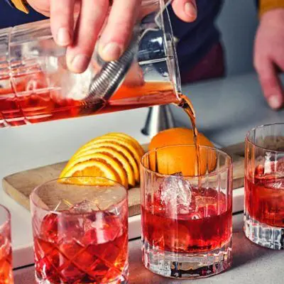 Pouring shot of on the rocks Negroni cocktails