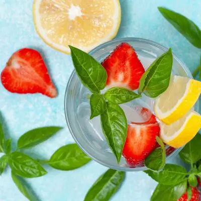 Top View of Strawberry Basil Cocktail garnished with fresh strawberries, basil and lemon slices