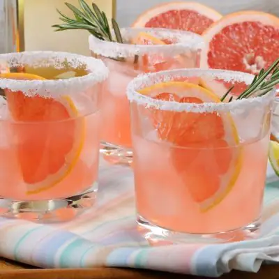 Close front view of a trio of refreshing pink paloma cocktails with grapefruit garnish