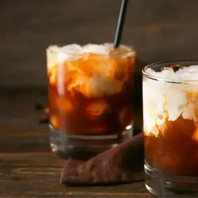 Two White Russian cocktails on a wooden board