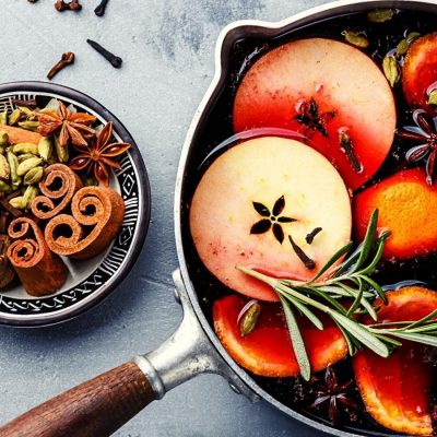 Top shot of mulled wine in a pot wit spices, citrus, herbs and fruit