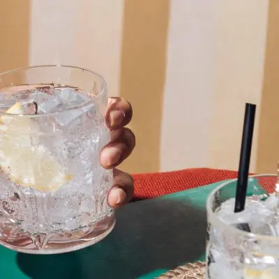 A woman's hand holding a tumbler filled with gin and tonic