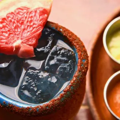 Cantarito Cocktail served in a clay cup with grapefruit and chili garnish