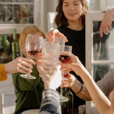 Friends clinking glasses together at kitchen table