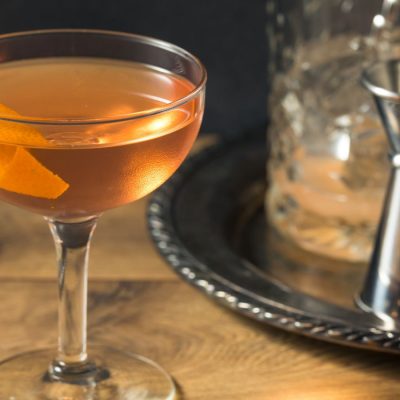 El Presidente Cocktail against a dark background featuring a fresh orange twist