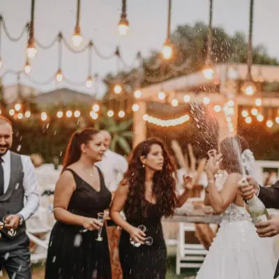 Groom popping a bottle of Champagne at wedding reception