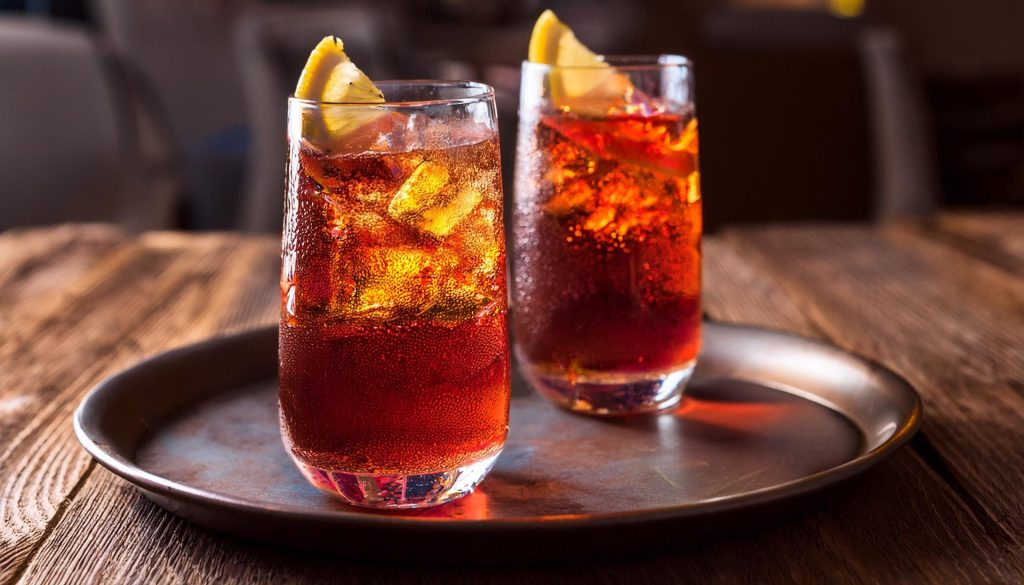 Close-up of two Americano cocktails in ice-filled highball glasses with lemon garnish